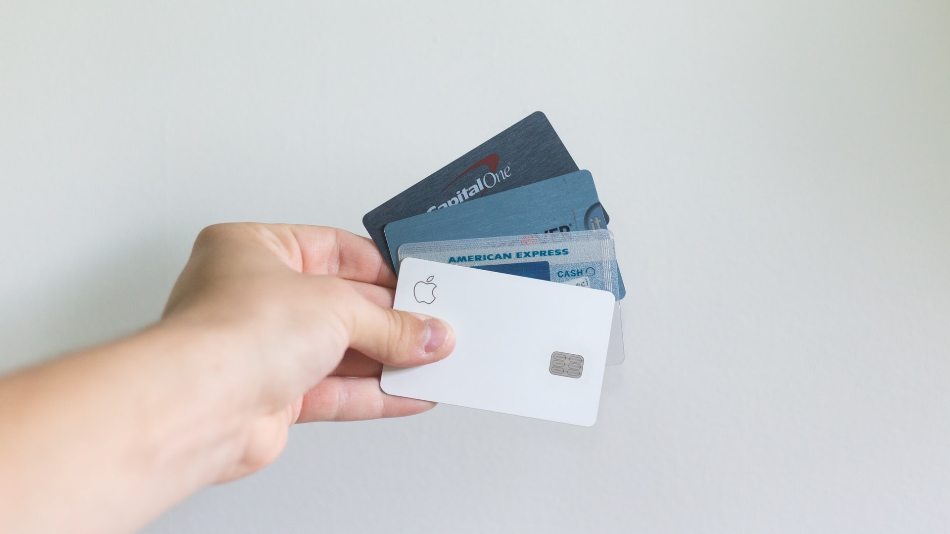 A person holding white and blue magnetic credit cards against a white background wall