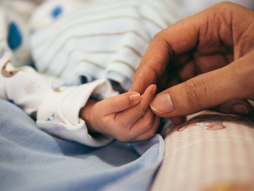 person holding baby's index finger in a hospital