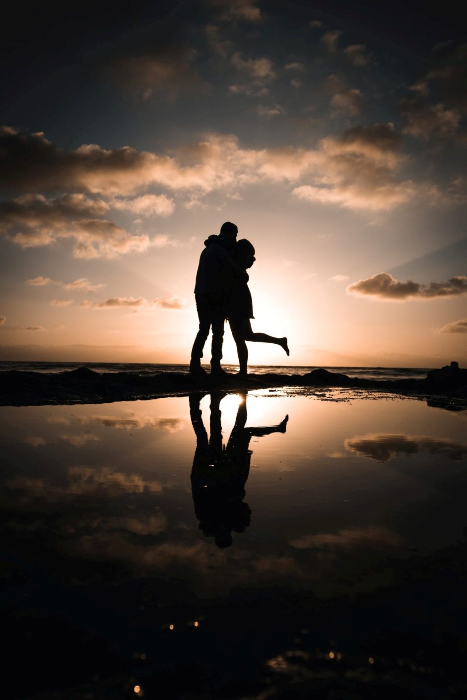 man and woman hugging on seoshore during sunset